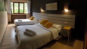 Habitación de hotel con dos camas, una mesita y una mesita de noche.