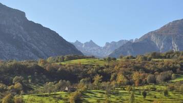Un paisaje montañoso con colinas verdes ondulantes y una pequeña casa al frente.