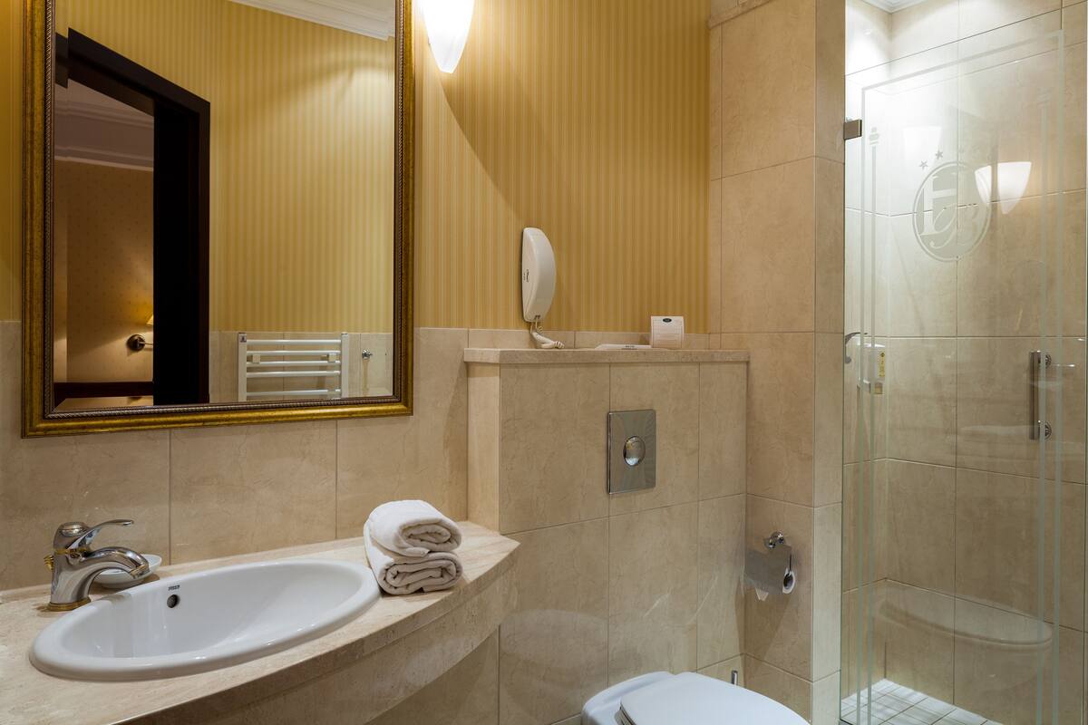 Ein Badezimmer mit Waschbecken, Spiegel, Handtuchhalter und einer Duschkabine.
