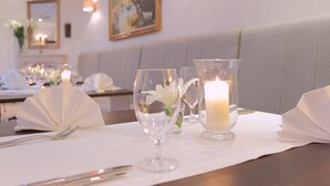 A dining table set with white napkins, clear glassware, and a lit candle. - Hotel Branicki (Bialystok)