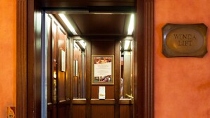 A wooden elevator with a clock above it, a sign reading "Winda Lift," and a patterned floor. - Hotel Branicki (Bialystok)