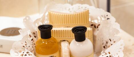 A tray with toiletries including a bottle of lotion, a bottle of soap, and a container of cream, surrounded by a decorative white lace doily.
