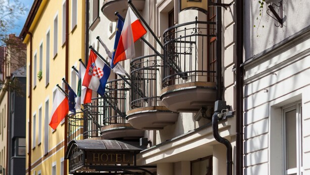 A hotel with a balcony, flags, and a sign. - Hotel Branicki (Bialystok)