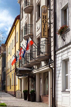 A hotel with a balcony, flags, and a sign. - Hotel Branicki (Bialystok)