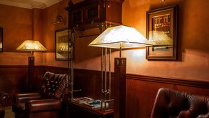 A room with a leather armchair, a floor lamp, and a table with books and magazines. - Hotel Branicki (Bialystok)