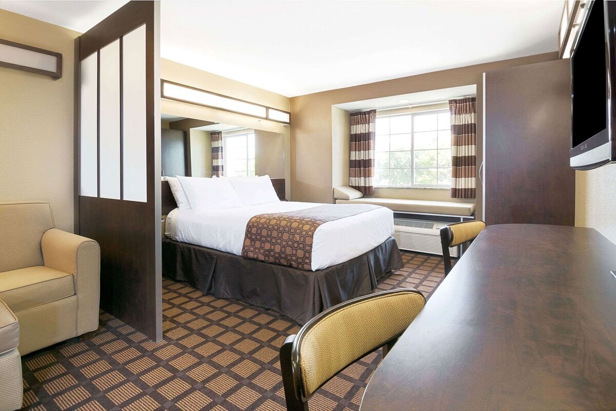 Ein Hotelzimmer mit einem Bett, einem Schreibtisch, einem Sessel und einem Fernseher.