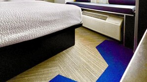 A hotel room with a bed, a window with curtains, a radiator, and a wall-mounted light fixture. - Microtel Inn & Suites by Wyndham Austin Airport (Austin)