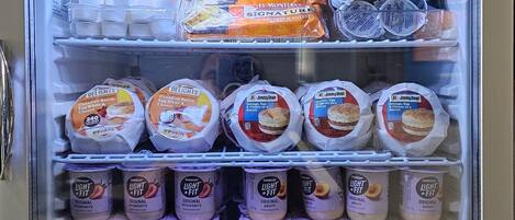 Vitrina refrigerada con diferentes productos alimenticios, como sándwiches, yogur y helado.