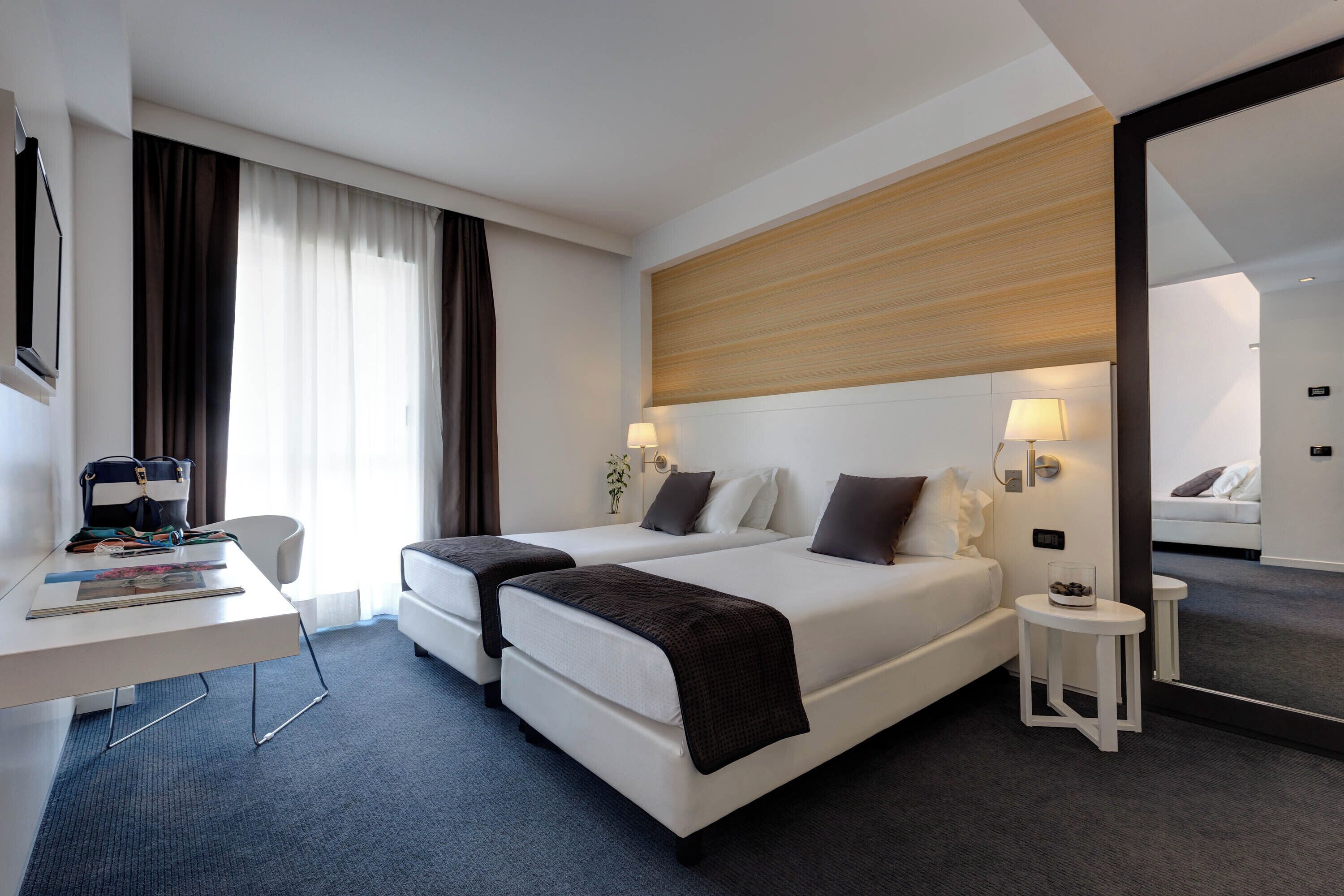 A modern hotel room with a large bed, a desk, and a small table.