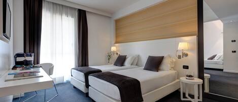 Una habitación de hotel moderna con una cama grande, un escritorio y una pequeña mesa.