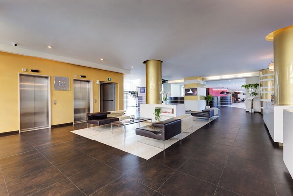 A spacious lobby with a reception desk, seating area, and elevators.
