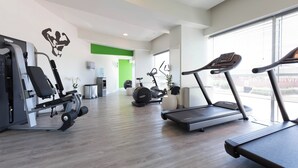 Una palestra con tapis roulant, macchinari per pesi e una parete verde.