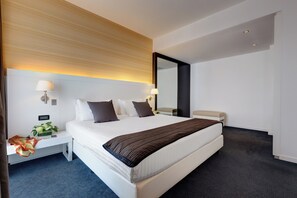A modern hotel room with a large bed, bedside tables, a mirror, and a nightstand.
