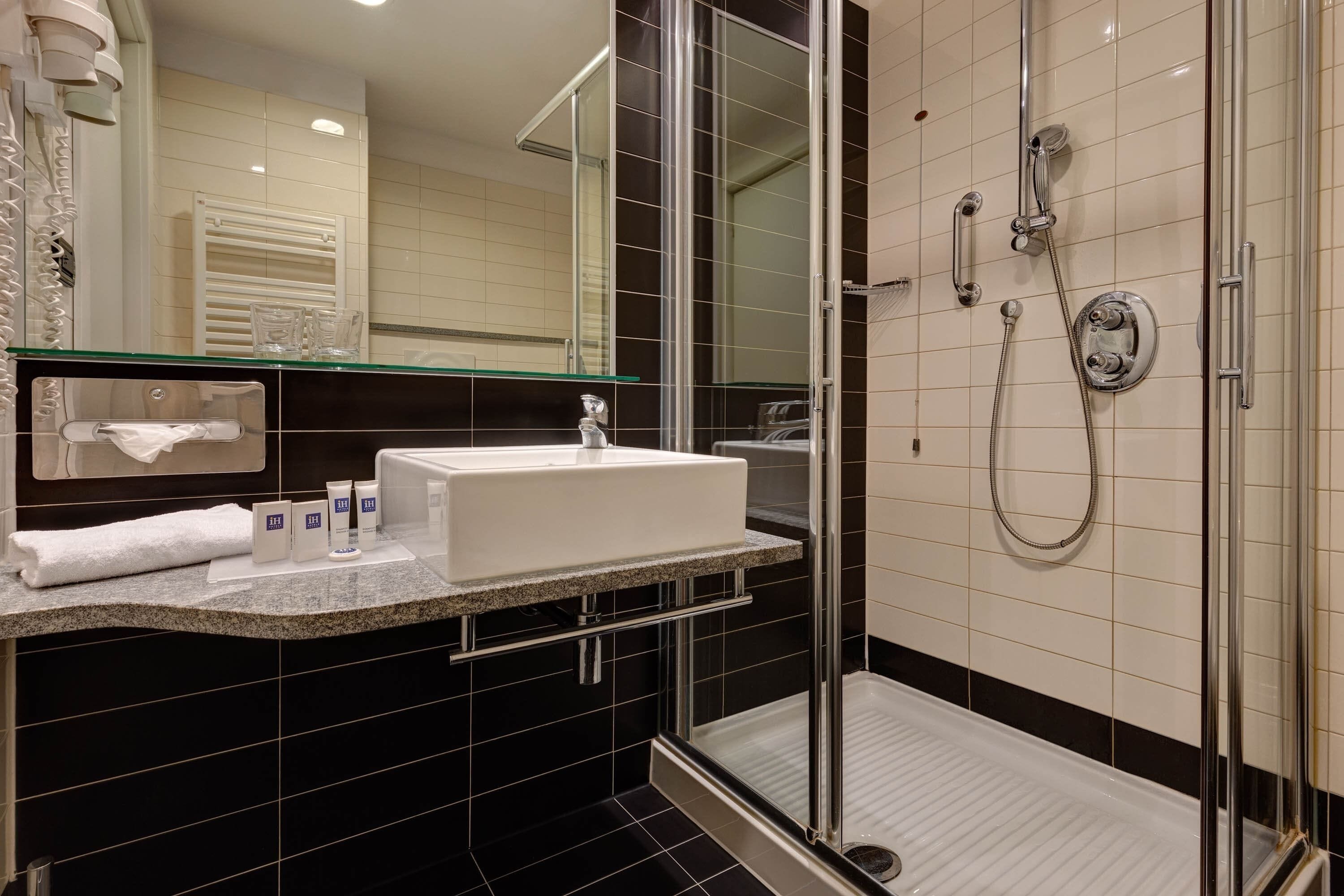 A modern bathroom with a glass-enclosed shower, a white sink, and a mirror above the sink.
