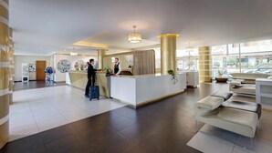 A modern hotel lobby with a reception desk, seating area, and large windows. - iH Hotels Roma Z3 (Rome)