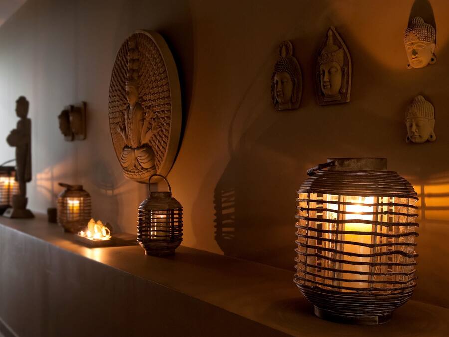 Um corredor com arandelas decorativas e estátuas de Buda fixadas na parede.