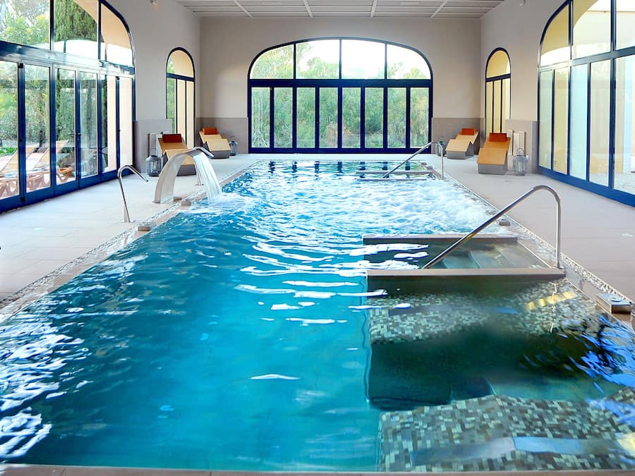 Een binnenzwembad, 4 buitenzwembaden en parasols bij het zwembad