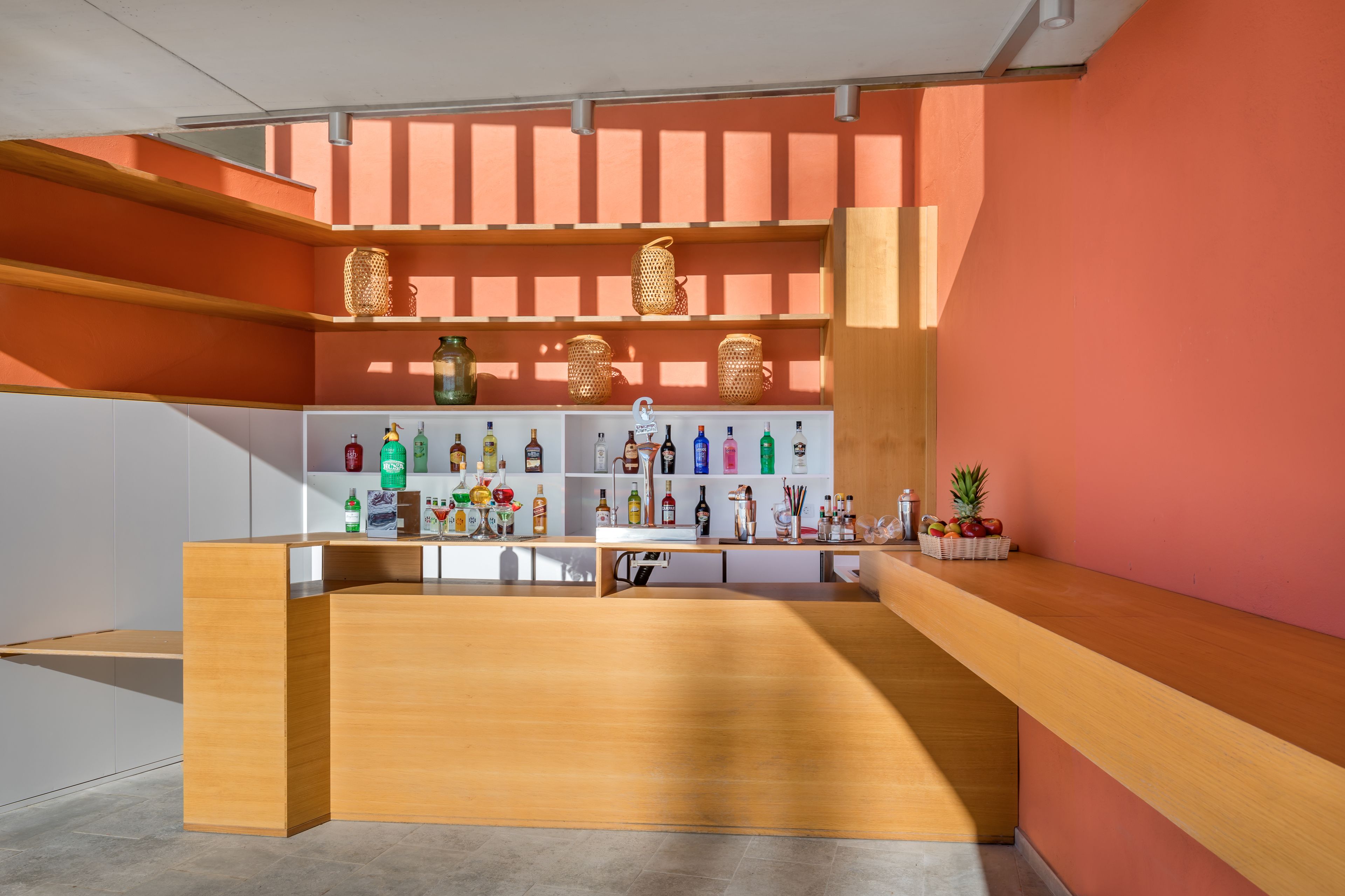 A bar area with wooden shelves displaying bottles and a fruit basket.