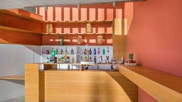 A bar area with wooden shelves displaying bottles and a fruit basket.