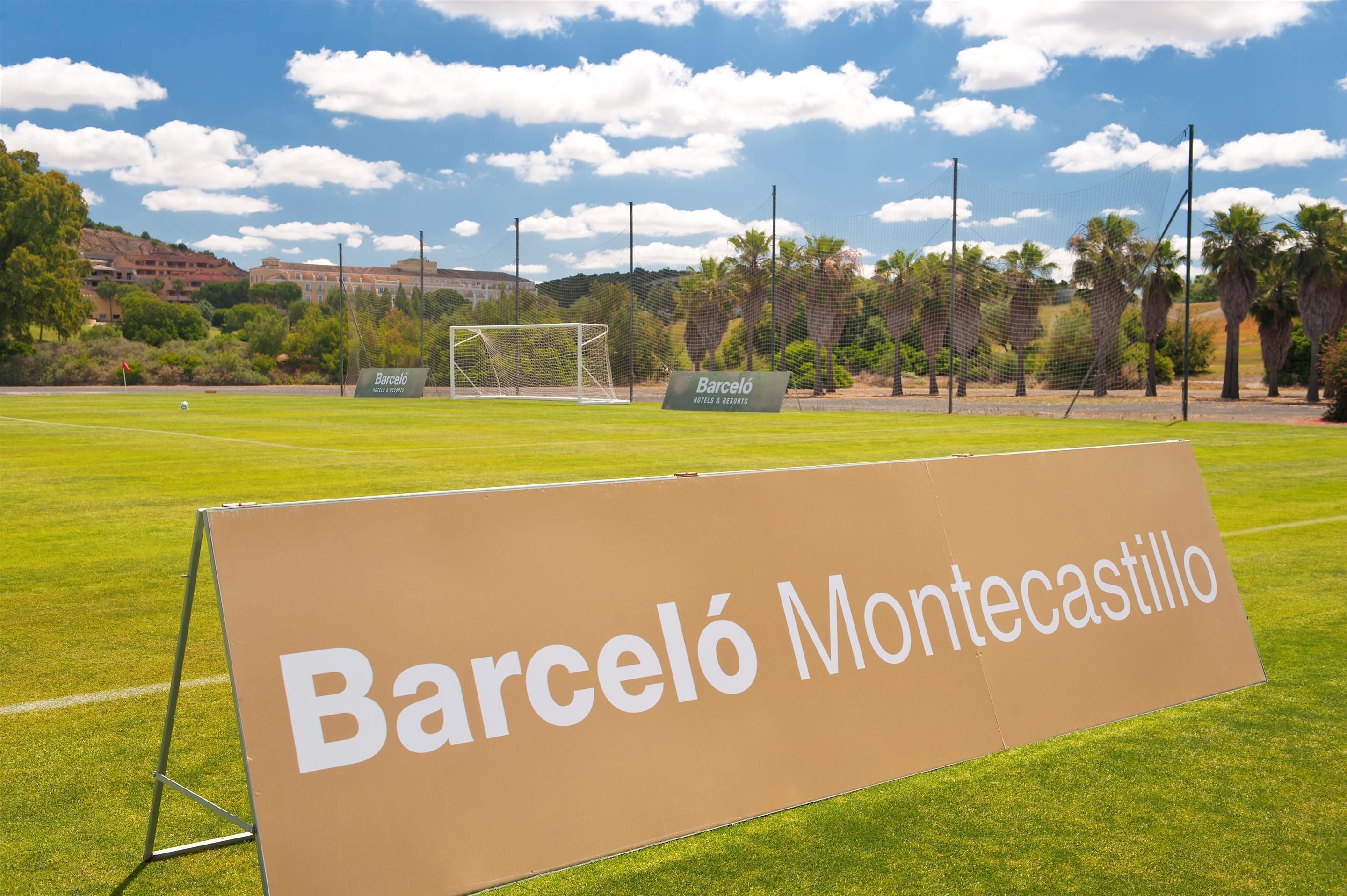 A sign for Barceló Montecastillo hotel on a grassy field with a soccer goal in the background.