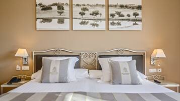 A hotel room with a large bed, two bedside tables, a nightstand, and three landscape paintings on the wall.