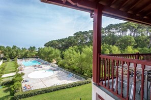 A pool area with a basketball court, surrounded by trees and a wooden deck. - Hotel Erromardie Plage by Odalys (Saint-Jean-de-Luz)