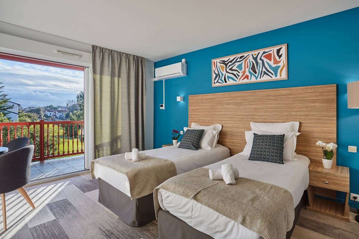 Ein Hotelzimmer mit zwei Betten, einem Balkon und einer blauen Wand.