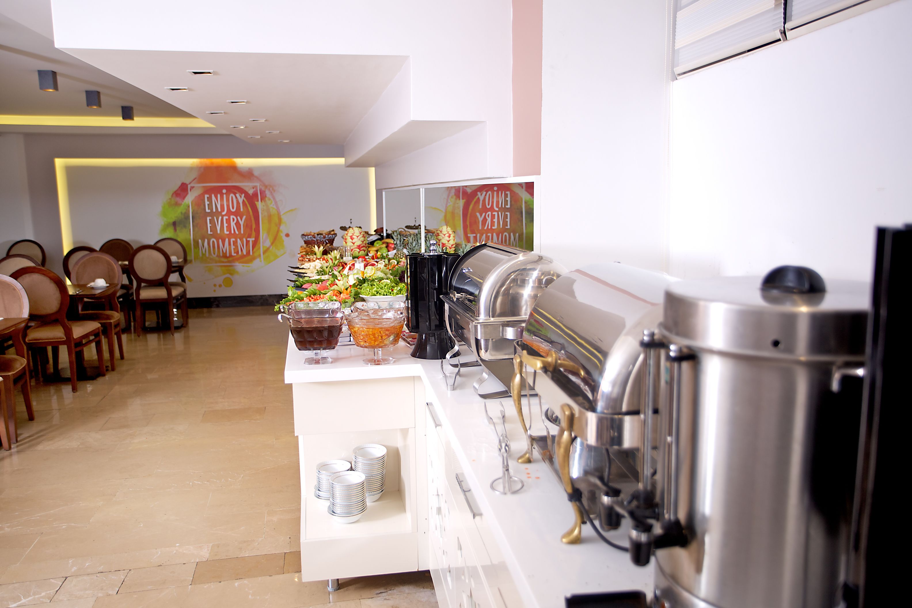 A buffet setup with a coffee machine, food bowls, and stacked plates.