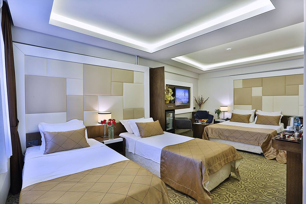 A hotel room with two beds, a TV, a desk, and a coffee machine.