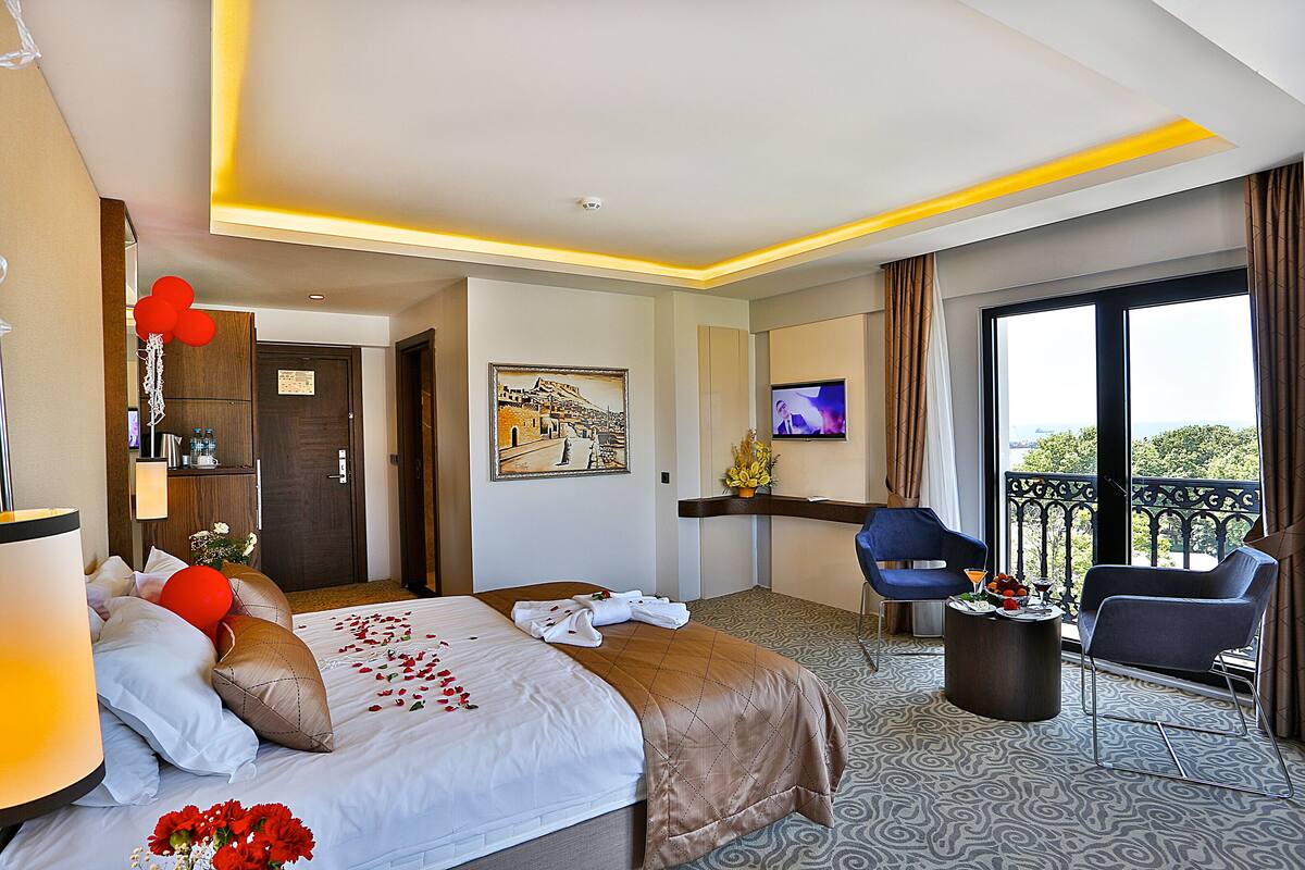 A hotel room with a bed, a desk, a TV, and a balcony with a view.