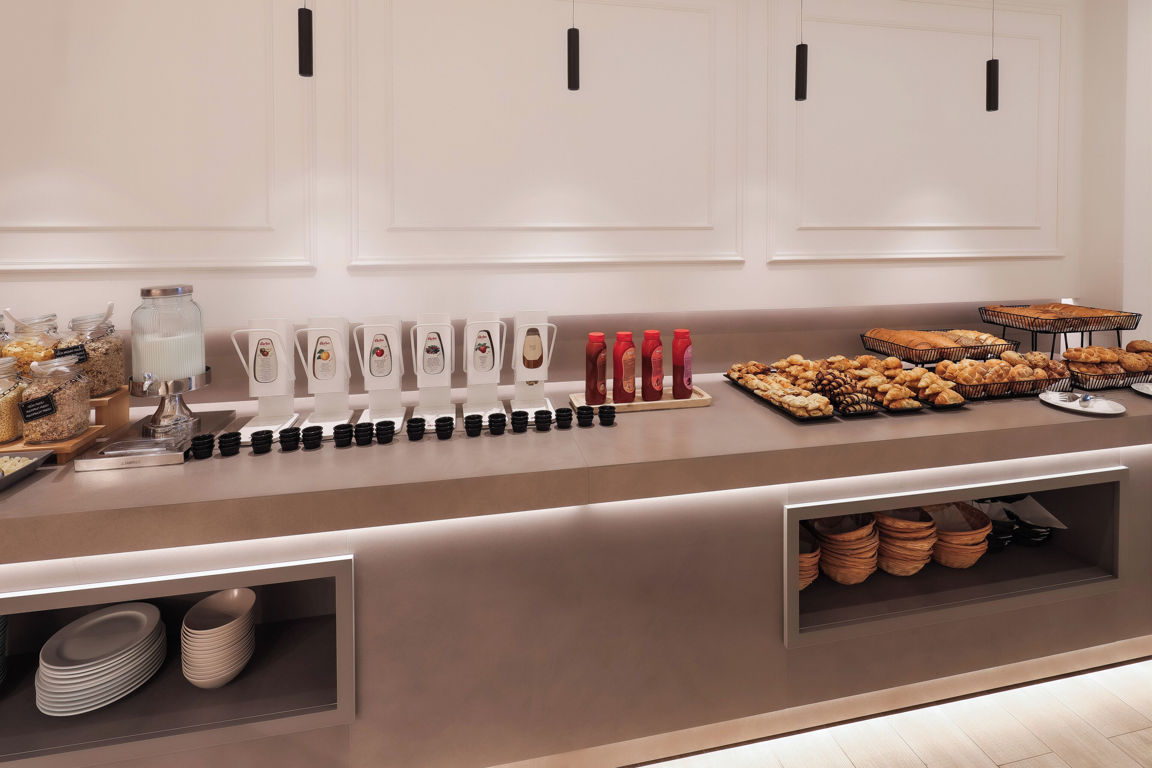 Una mesa de buffet con diversos alimentos, salsas y utensilios para servir.