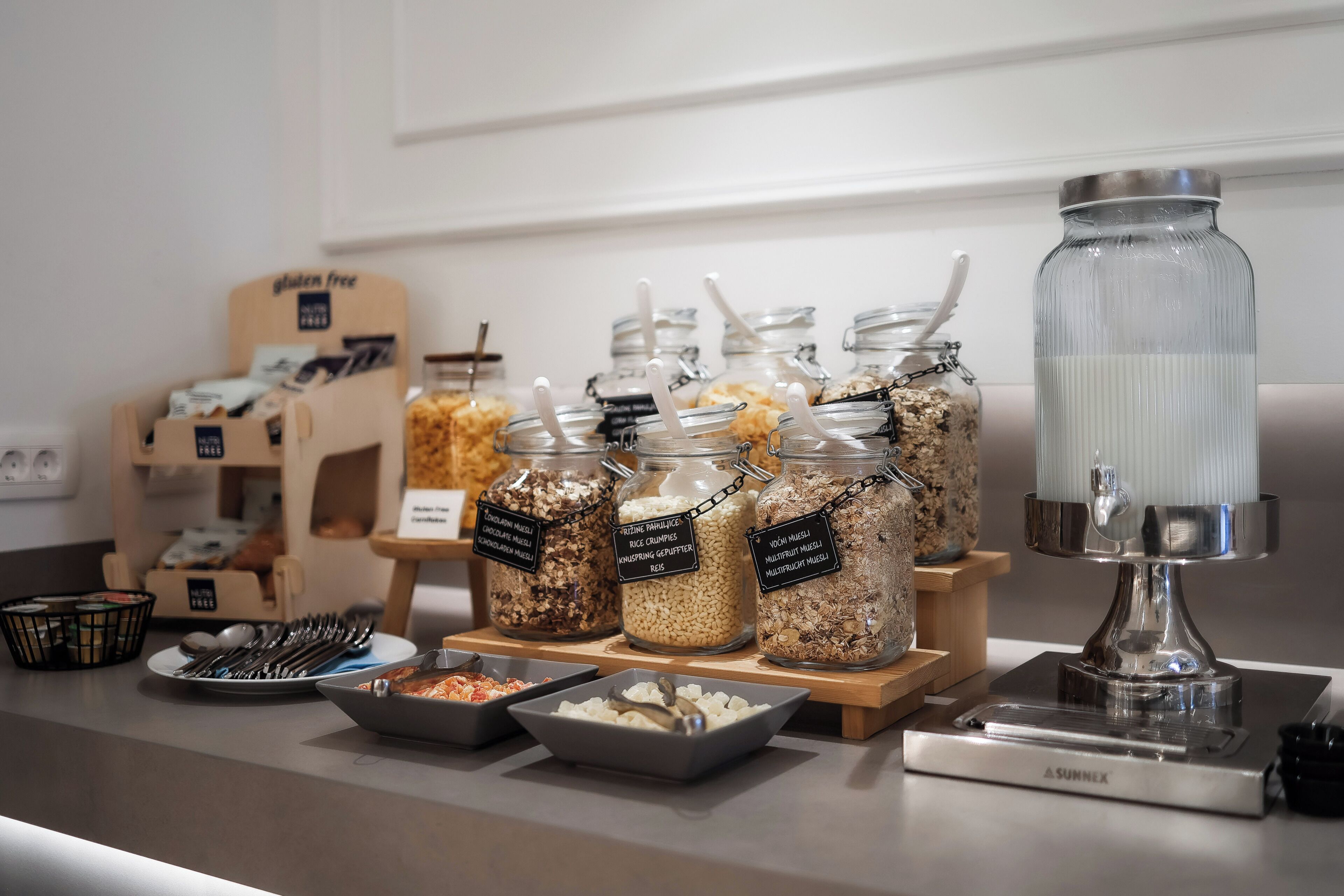 A buffet setup with various food items in jars and bowls, a water dispenser, and a coffee machine.