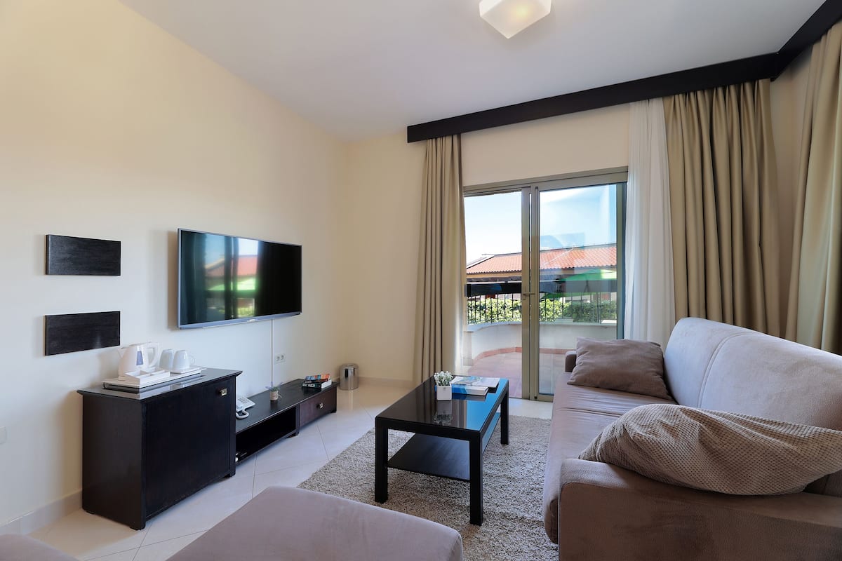 Una sala de estar moderna con un televisor de pantalla plana, un mueble de entretenimiento negro, un sofá y una mesa de centro.
