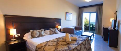 A hotel room with a large bed, a desk, a chair, and a view of the outdoors.