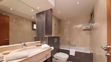 Un baño moderno con un espejo grande, un lavamanos, un inodoro y una zona de ducha.