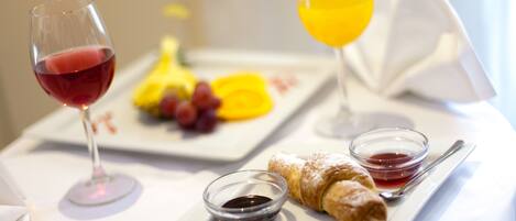 Desayuno con un croissant, fruta y dos vasos de bebida sobre un mantel blanco.