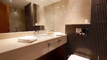 A modern bathroom with a large mirror, a sink, and a toilet.