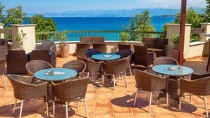 An outdoor seating area with wicker furniture and a view of the sea. - Blue Waves Resort (Malinska-Dubasnica)