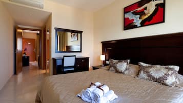 A hotel room with a large bed, a desk, a chair, a dresser, and a painting on the wall.