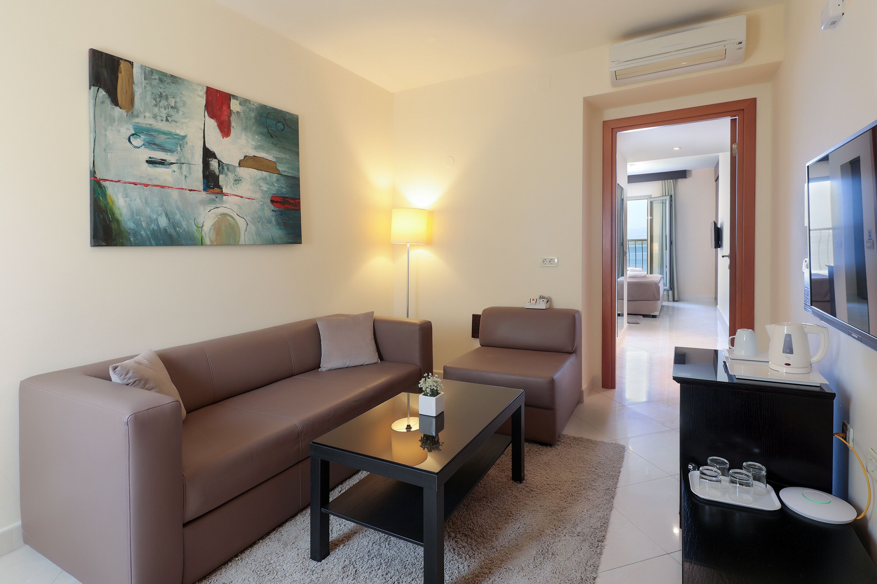 Ein modernes Wohnzimmer mit einer Couch, einem Sessel, einem Couchtisch und einem Bild an der Wand.