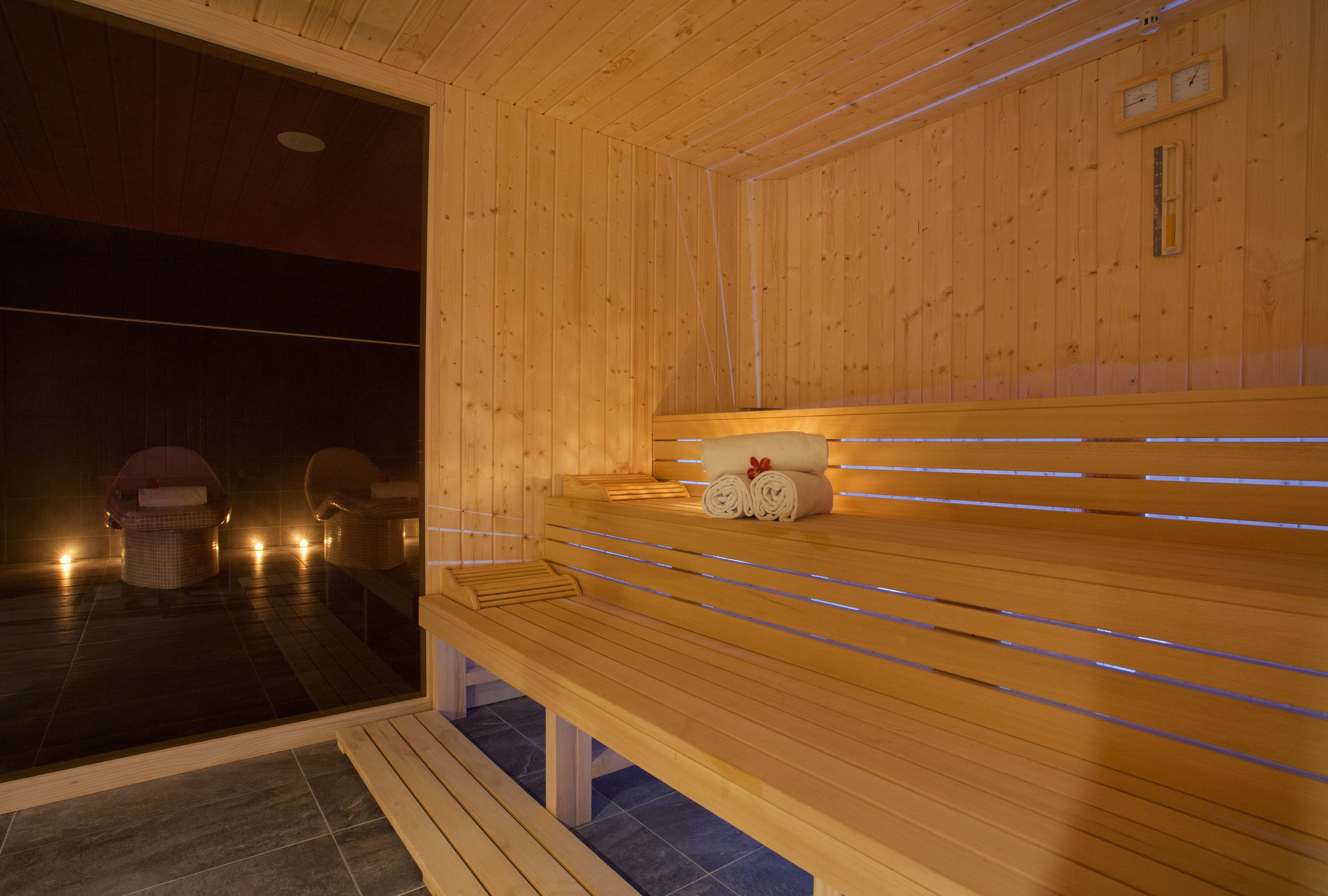 Un sauna en bois avec des bancs et un banc où sont disposées des serviettes.