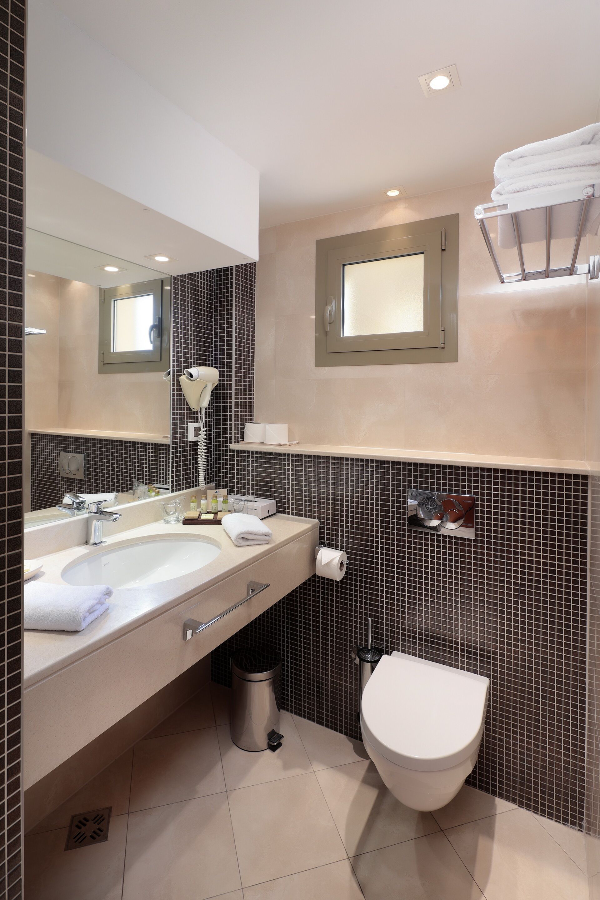 Un bany modern amb un lavabo doble, un assecador, una barra de tovalloles i un vàter.
