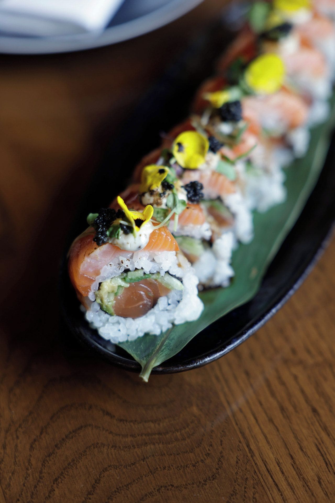 Ein Sushi-Gericht mit verschiedenen Belägen auf einem schwarzen Teller.