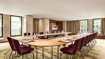 Un salón de conferencias con una mesa larga, sillas y piso alfombrado.