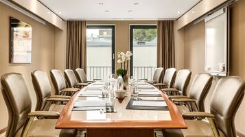 A conference room with a long table, multiple chairs, and a vase with flowers.