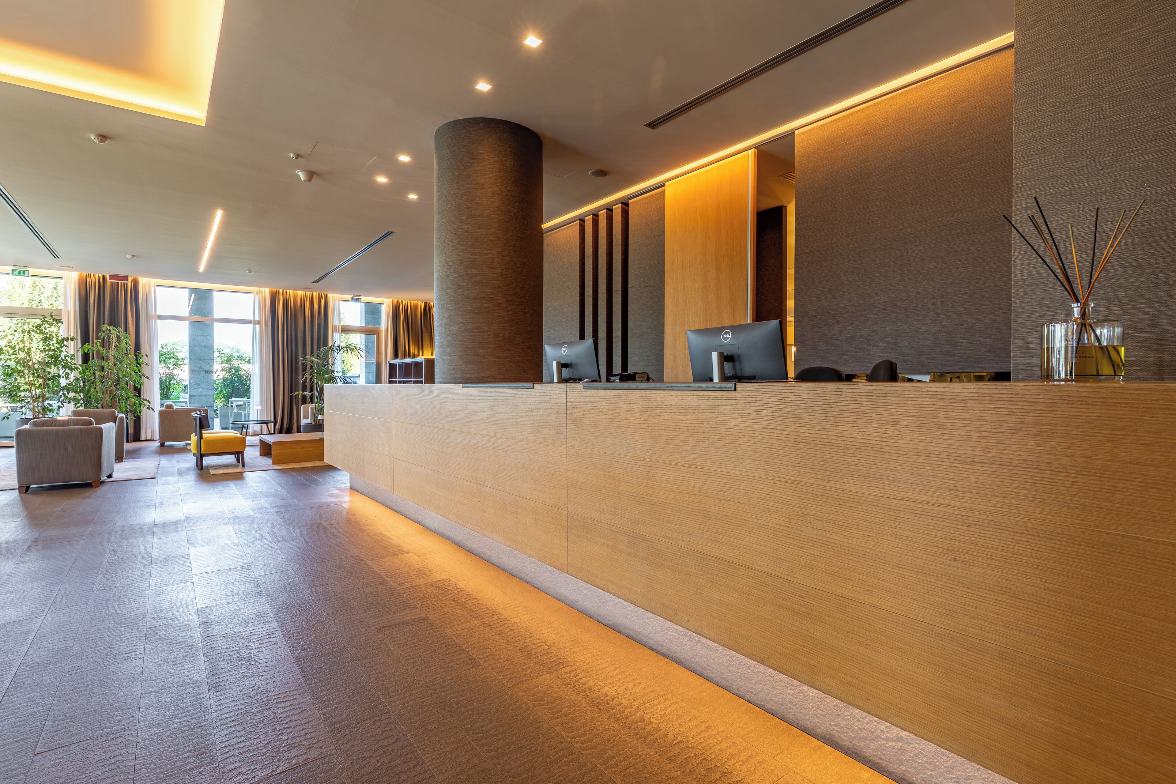 A modern reception area with a long counter, two computer stations, and a large pillar.