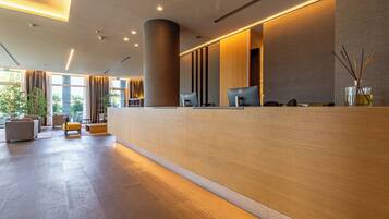 A modern reception area with a long counter, two computer stations, and a large pillar.