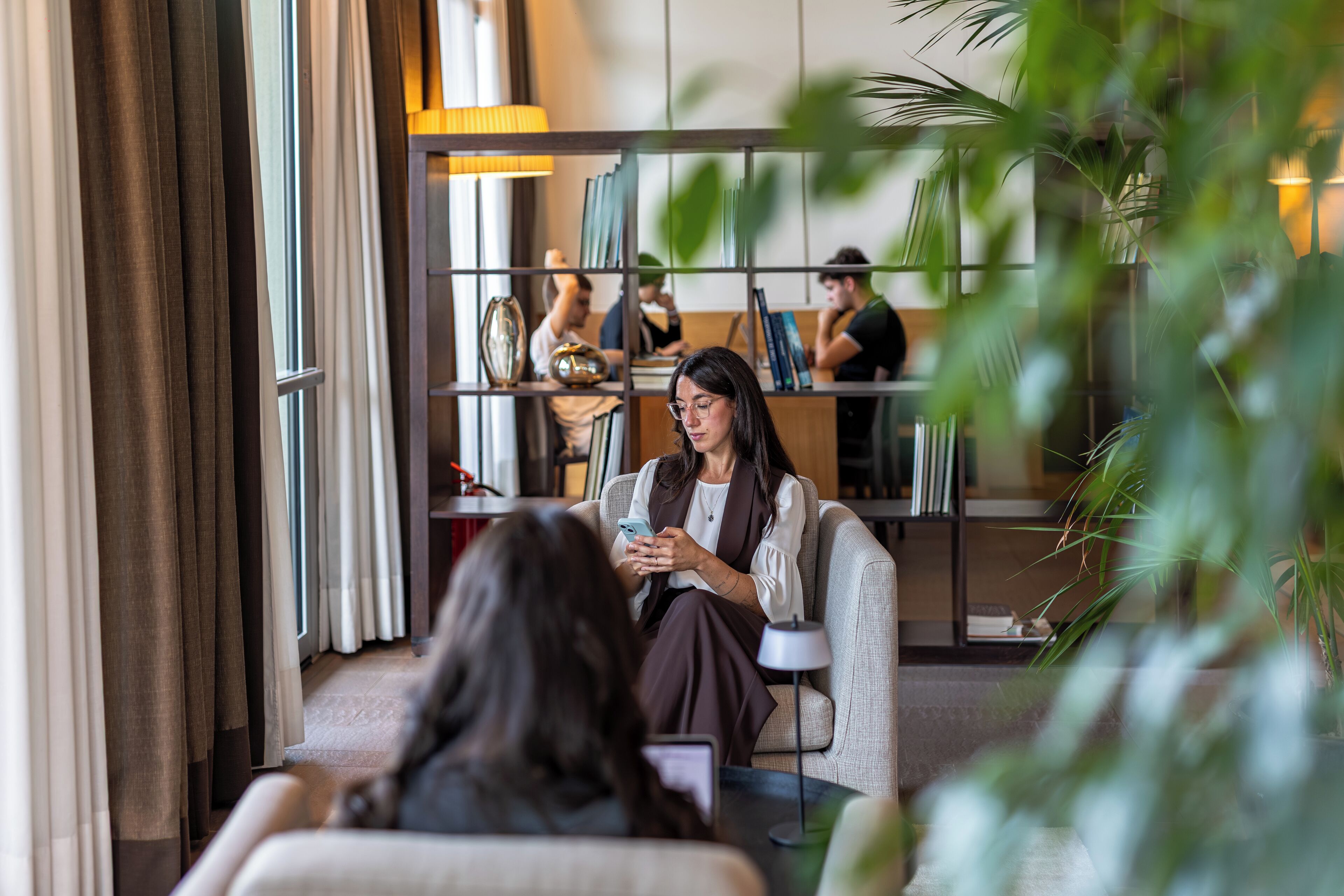 A modern lobby with a seating area, a reception desk, and a bookshelf.