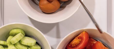 Two bowls, one with sliced cucumbers and the other with sliced tomatoes.