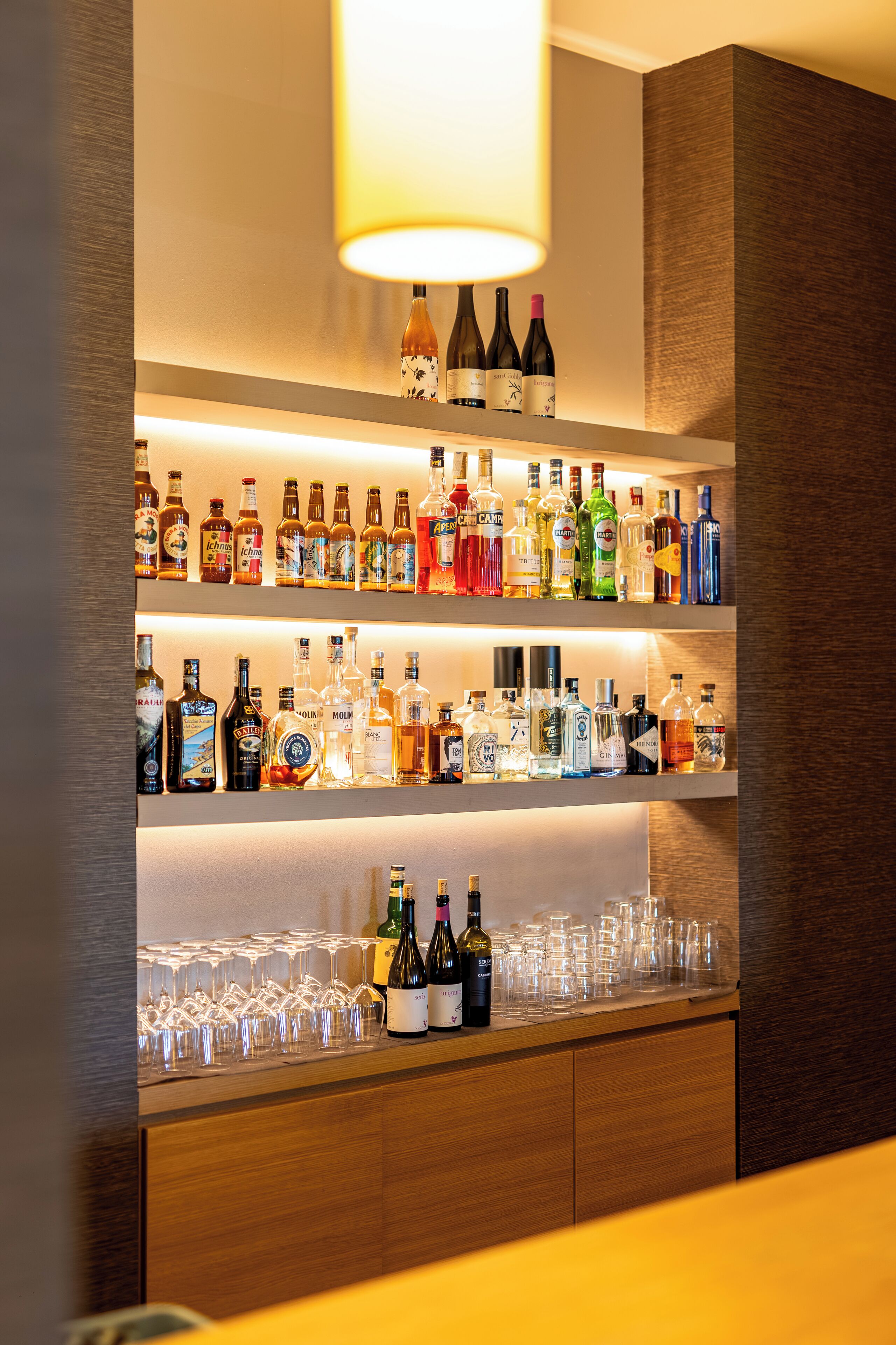 Angolo bar con scaffali pieni di bottiglie di liquori e bicchieri.